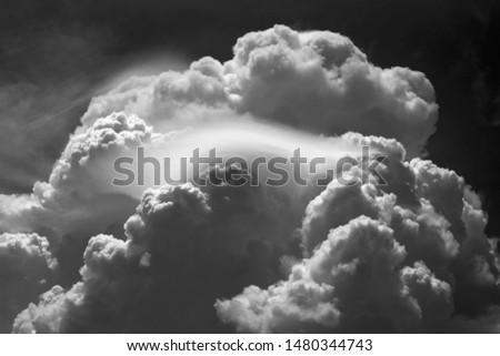 Beautiful dramatic mountainous fluffy storm clouds with wispy clouds in the center. High contrast black and white image.