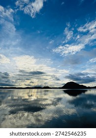Beautiful dramatic sky with cloud reflections over calm lake water in Giriulla, Sri Lanka. Peaceful tropical landscape with blue sky, natural scenery and serene water reflection during sunset. Ideal for travel, nature and background use.