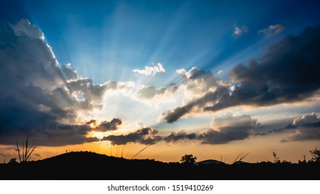 the beautiful dramatic sky with sun rays over silhouette mountain