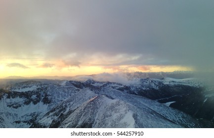 Beautiful dramatic sky with sun rays and clouds over a winter mountain.