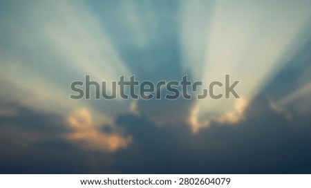Beautiful dramatic sun rays piercing through dark clouds during a vibrant sunset, creating a celestial and awe-inspiring scene.