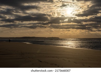 Beautiful dramatic sunset at goldenhour with some large clouds above the beautiful seashore with slight waves coming in, beautiful landscape. High quality photo