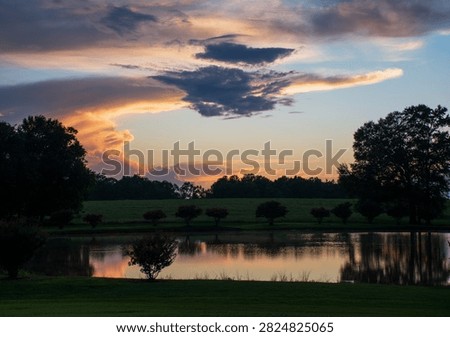 A beautiful dramatically cloudy sunset reflecting off of an Alabama pond