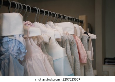 Beautiful Dressy Lush Pink And Blue Dresses For Girls On Hangers At The Background Of White Wall. Kids Dresses With Feathers For Prom And Holiday.