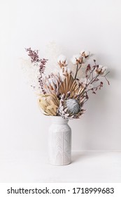 Beautiful dried flower arrangement in a stylish ceramic white vase. Dried flowers include pink proteas, banksia, gold palm leaf, kangaroo paw, cotton and ruscus leaves.