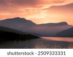 Beautiful dusk sunset scenic view toward misty mountains and lake, Glyderau, the Gylders at the lakeshore of Llyn Ogwen, Ribbon Lake in Wales, Eryri, Snowdonia National Park, UK