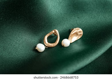 Beautiful earrings on green fabric background