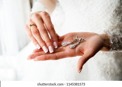 Beautiful earrings on the palm of the bride
