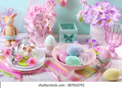 beautiful easter table decoration with eggs in bowl,flowers ,rabbit and lamb figurines in pastel colors
