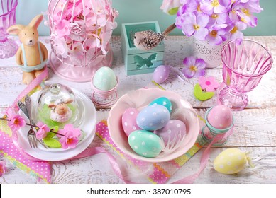 beautiful easter table decoration with eggs in bowl,flowers ,rabbit and lamb figurines in pastel colors 