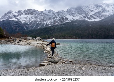 beautiful Eibsee mountain lake in Grainau Germany with Zugspitze mountains in the background tourist woman walking on rock pathway .