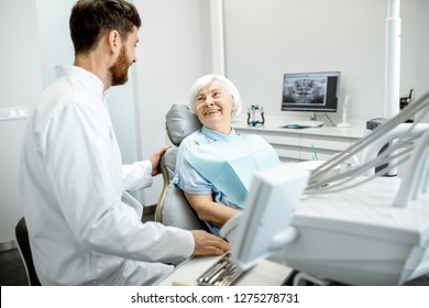 Beautiful elder woman with healthy smile sitting during the consultation with dentist at the dental office - Powered by Shutterstock