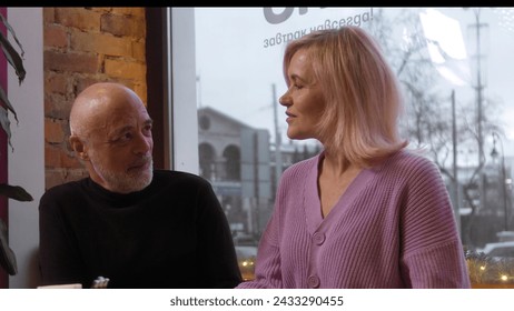 Beautiful elderly couple is chatting in cafe. Stock footage. Elderly couple is chatting sweetly on date in cafe. Beautiful couple on date in cozy cafe - Powered by Shutterstock