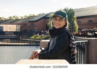 Beautiful Elderly Woman In  Cap And  Black Raincoat By  Embankment