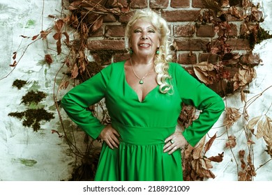 Beautiful Elderly Woman In An Elegant Summer Green Dress Poses On A Vintage Background. Granny Fashion Model.