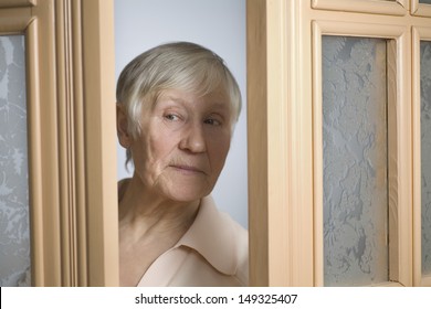 Beautiful Elderly Woman Peeking Through Doorway At Home