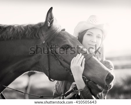Beautiful elegance back woman cowgirl nearby muzzle horse. Has haired hair, brown leather jacket and hat. Has slim body. Portrait nature. People and animals. Equestrian. Close up riding