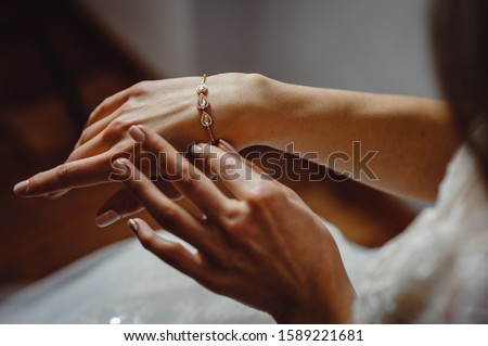 Beautiful elegant bride puts a bracelet on her hand, closeup. Girl put a bracelet on arm.Preparing the bride for the wedding ceremony.