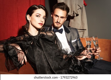 Beautiful Elegant Couple In Fashionable Evening Clothes Drinking Champagne In A Luxury Apartment. Glamorous Lifestyle. Fashion Shot.