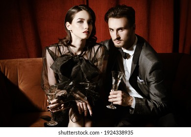 Beautiful Elegant Couple In Fashionable Evening Clothes Drinking Champagne In A Luxury Apartment. Glamorous Lifestyle. Fashion Shot.