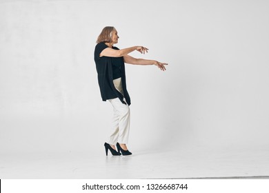 Beautiful Elegant Elderly Woman Dancing In A Black Sweater In Full Growth On A Gray Background