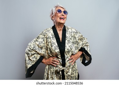 beautiful and elegant old influencer woman. Cool grandmother posing in studio wearing fashionable clothes. Happy senior lady celebrating and making party. Concept about seniority and lifestyle