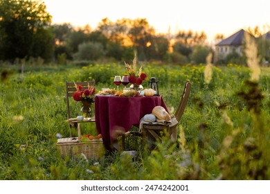 Beautiful elegant outdoor romantic dinner table decor countryside style: pumpkins, candles, flowers, red wine, gourmet cheese board. Cozy garden interior, open air party event. Sunset golden hour - Powered by Shutterstock