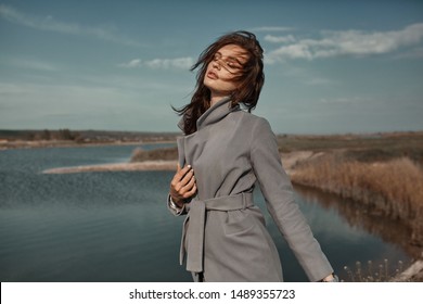 Beautiful elegant portrait of young woman in fashion grey coat outside. Sunny autumn ar spring weather. 