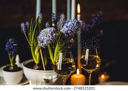Beautiful elegant table setting for Easter celebration with fresh spring hyacinth flowers, burning candles. Romantic wedding dinner table decoration. Springtime, home gardening. Dark background