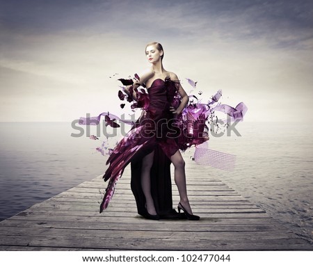 Beautiful elegant woman on a wharf with her dress melting away