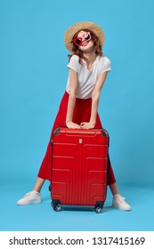 Beautiful elegant woman with a red suitcase on a blue background travel hop - Shutterstock ID 1317415169