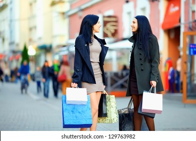 beautiful elegant women walking the crowded city street with shopping bags