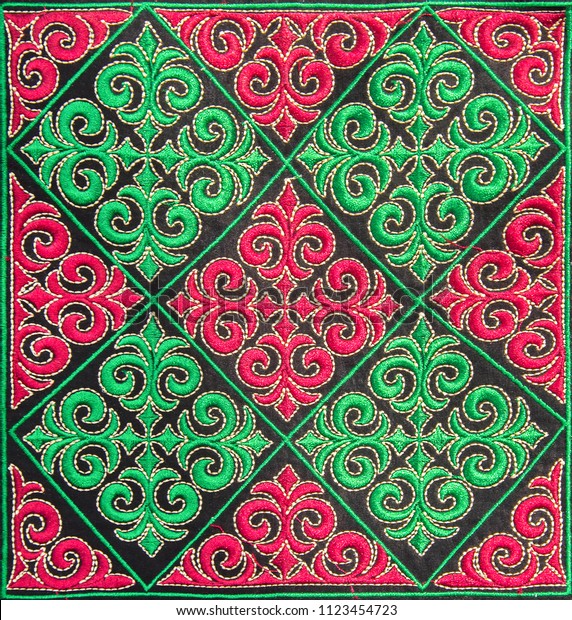 Beautiful\
embroidery in Kazakh style made of red & green squares on\
black velvet. Closeup. Selective\
focus