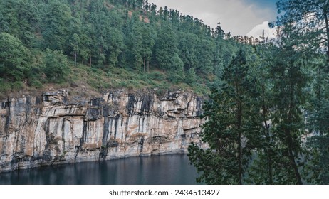 A beautiful emerald lake with steep rocky shores in the crater of an extinct volcano. A lush coniferous forest grows on the mountainside. Tritriva Lake. Madagascar. - Powered by Shutterstock