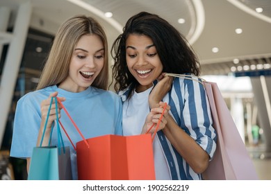 Beautiful emotional women holding shopping bags in shopping centre. Big sales concept 