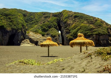 Beautiful empty secluded lonely sand beach,  thatch palapa umbrellas, crevice gap in rock (Iglesia de Piedra) - Cobquecura de la Loberia, Chile 