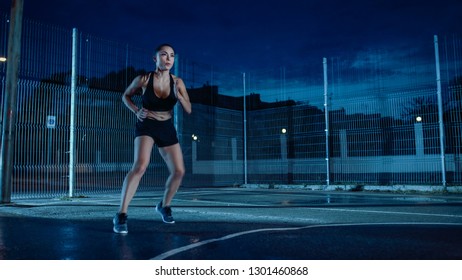 Beautiful Energetic Fitness Girl Doing Footwork Running Drill. She is Doing a Workout in a Fenced Outdoor Basketball Court. Night After Rain in a Residential Neighborhood Area. - Powered by Shutterstock