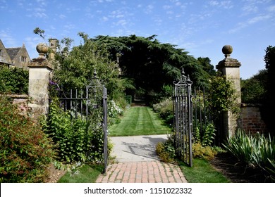 Beautiful English parks and gardens in summer time . English countryside.  Walk ways and green lawns , beautiful rough iron gates and gate posts. A sun dail and flowers , hedges and trees.