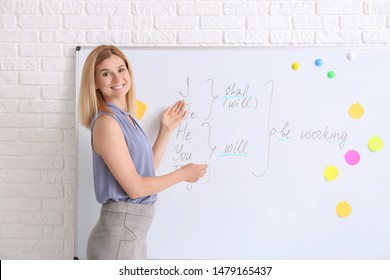 Beautiful English Teacher Near Board In Classroom