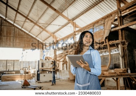 Beautiful entrepreneurial woman working with digital tablet in wood craft workshop