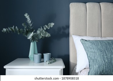 Beautiful eucalyptus branches and candles on nightstand in bedroom. Interior element