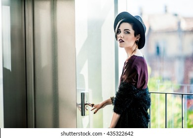 Beautiful European Woman With Black Hair And Dark Lipstick Standing Near The Elevator And Pressing The Button