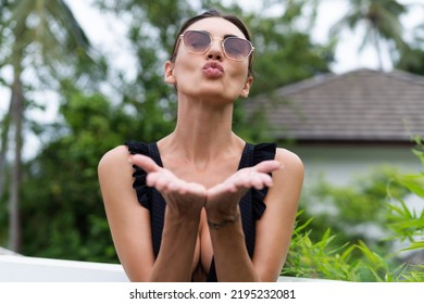 Beautiful European Woman In Black Swimsuit Posing Outside At Villa In Swimming Pool, On Vacation, Tanned, Wearing Trendy Brown Sunglasses. Close Portrait. Natural Soft Skin.