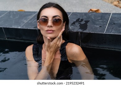 Beautiful European Woman In Black Swimsuit Posing Outside At Villa In Swimming Pool, On Vacation, Perfect Shape, Good Body, Tanned, Fit, Wearing Trendy Brown Sunglasses