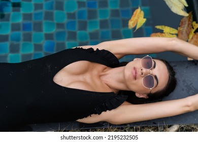 Beautiful European Woman In Black Swimsuit Posing Outside At Villa In Swimming Pool, On Vacation, Perfect Shape, Good Body, Tanned, Fit, Wearing Trendy Brown Sunglasses