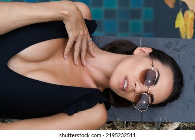 Beautiful European Woman In Black Swimsuit Posing Outside At Villa In Swimming Pool, On Vacation, Perfect Shape, Good Body, Tanned, Fit, Wearing Trendy Brown Sunglasses