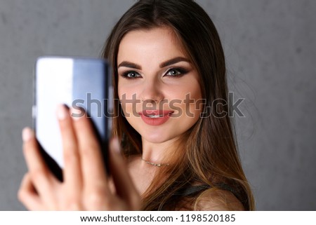 Beautiful european woman portrait. Worth a gray background uses a smartphone makes selfie and reads messages from social networks and messengers