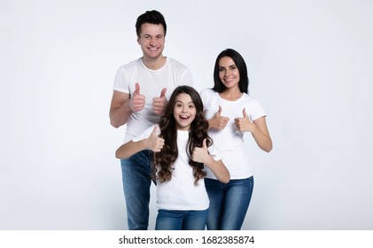 Beautiful Excited And The Funny Family Team Is Posing And Showing Thumbs Up In A White T-shirt While They Isolated On White Background In Studio.