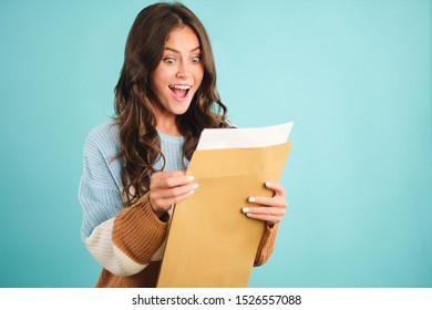 Beautiful Excited Girl In Cozy Sweater Happily Opening Response Envelope Over Blue Background