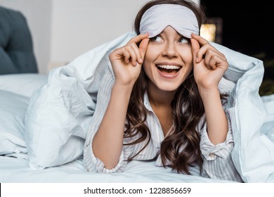 Beautiful Excited Girl In Sleeping Eye Mask Lying In Bed